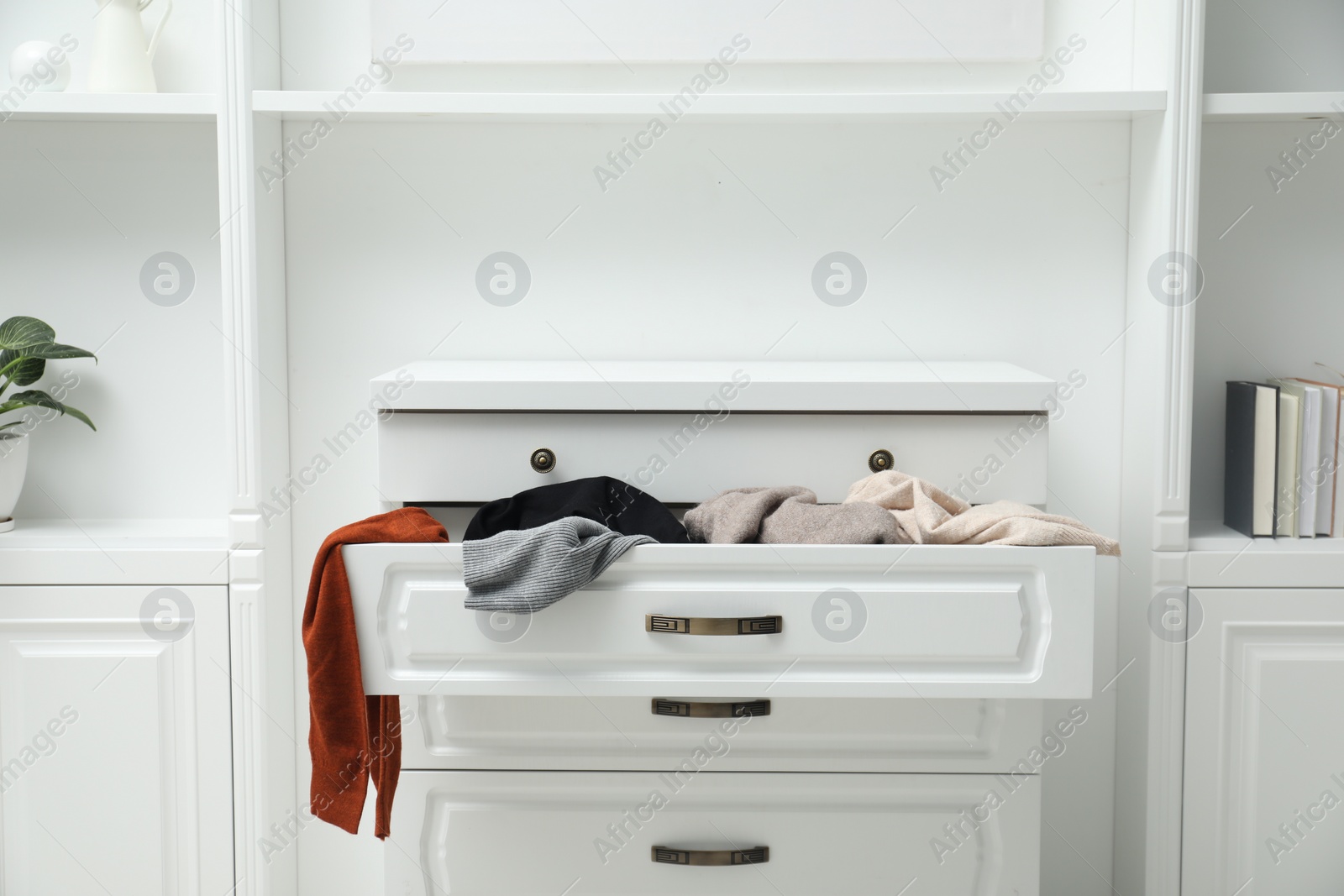 Photo of Cluttered chest of drawers indoors. Clothes in mess