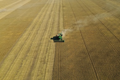 Photo of Beautiful aerial view of modern combine harvester working in field on sunny day. Agriculture industry