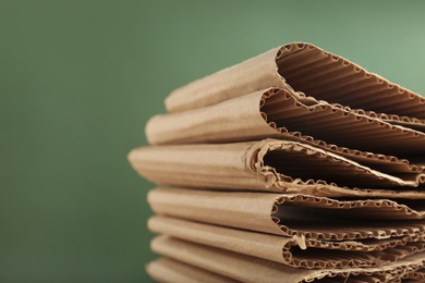 Photo of Stack of cardboard on green background, closeup with space for text. Recycling concept