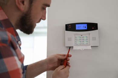 Man installing home security system on white wall in room, closeup