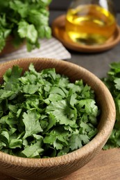 Photo of Cut fresh green cilantro in wooden bowl on board, closeup