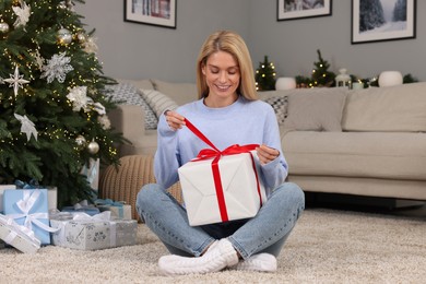 Photo of Happy woman opening Christmas gift at home