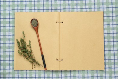 Blank recipe book and thyme on checkered tablecloth, top view. Space for text