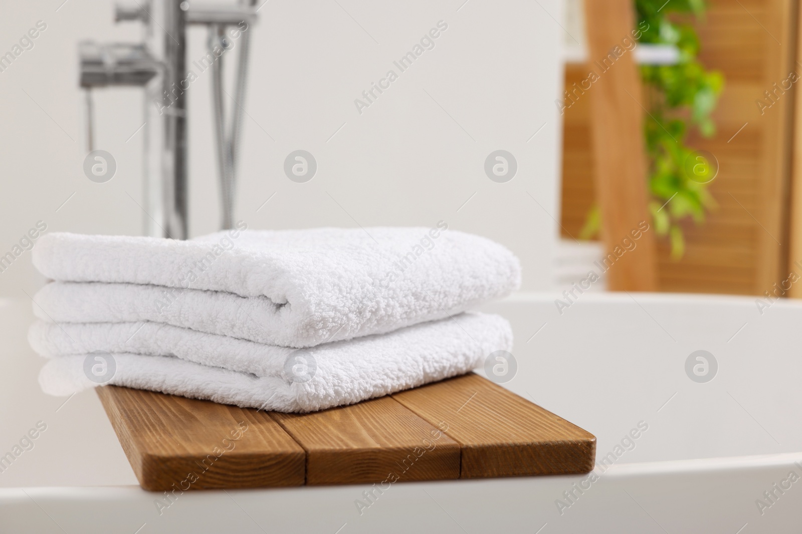 Photo of Stacked soft towels on tub tray in bathroom