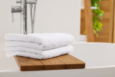 Stacked soft towels on tub tray in bathroom