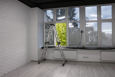 Photo of Ladder in empty renovated room with windows