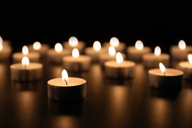 Burning candles on table in darkness, space for text. Funeral symbol