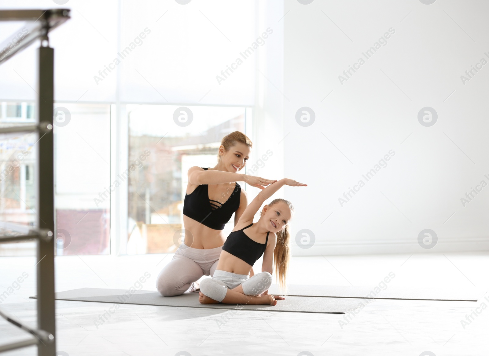 Photo of Mother and daughter in matching sportswear doing yoga together at home