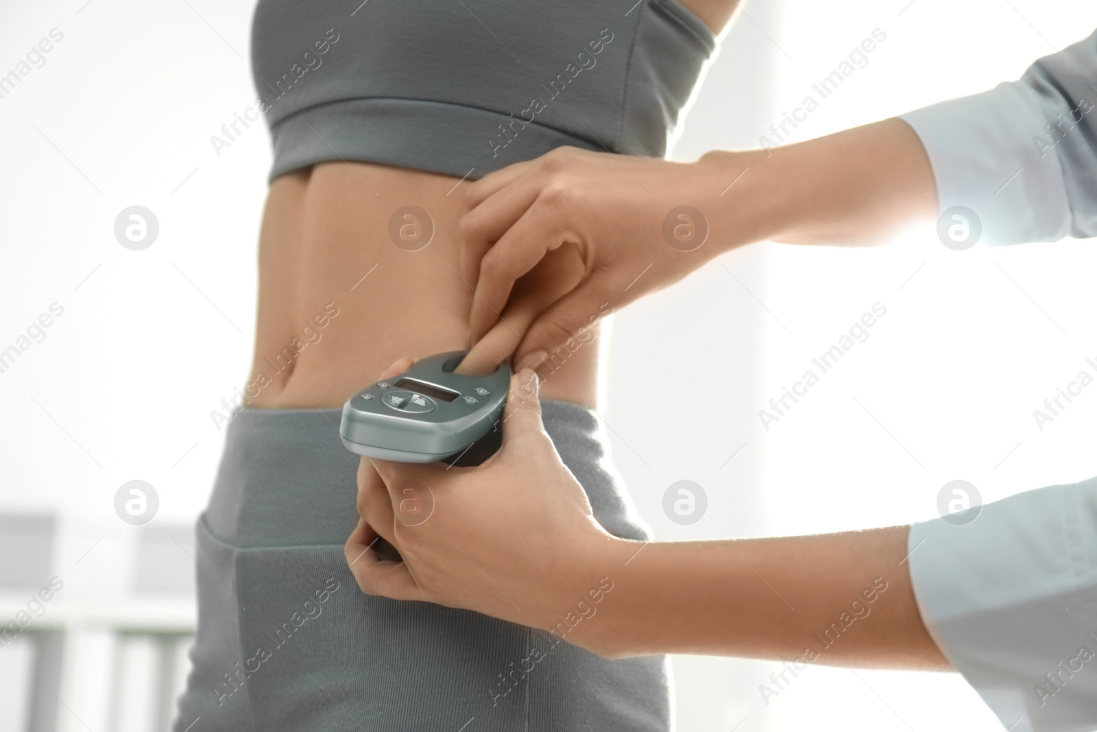 Photo of Nutritionist measuring woman's fat layer with caliper indoors, closeup