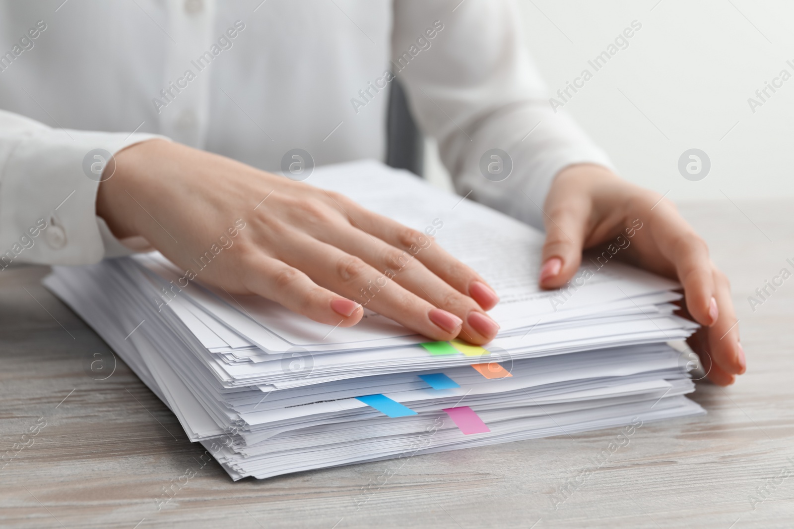 Photo of Woman stacking documents at wooden table in office, closeup