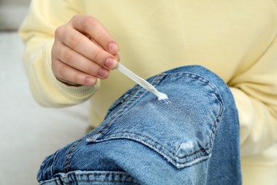 Photo of Woman removing chewing gum from jeans, closeup