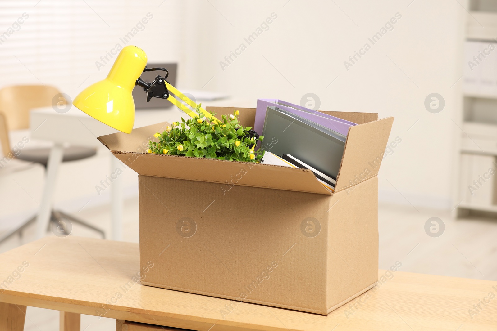 Photo of Unemployment problem. Box with worker's personal belongings on desk in office