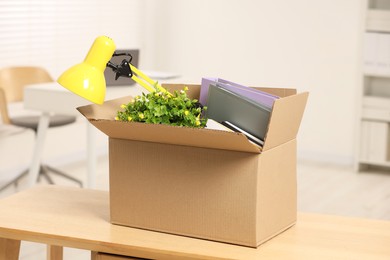 Photo of Unemployment problem. Box with worker's personal belongings on desk in office
