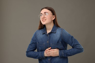 Photo of Woman suffering from stomach pain on grey background