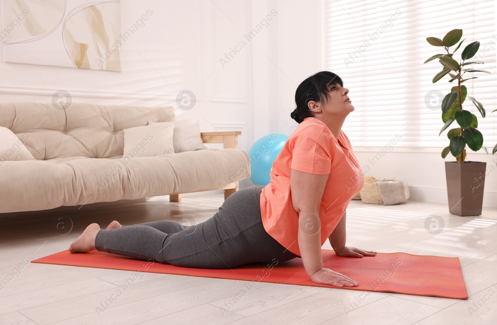 Photo of Overweight mature woman doing exercise on yoga mat at home