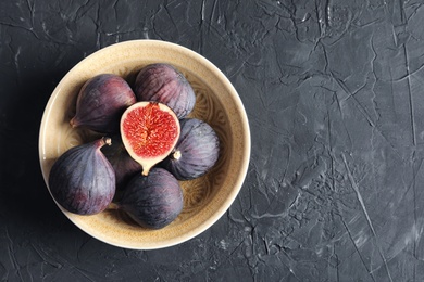 Photo of Bowl with fresh ripe figs on dark background, top view. Space for text