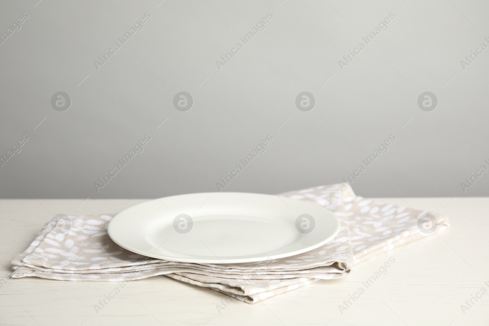 Photo of Empty plate and napkin on white table against grey background. Space for text