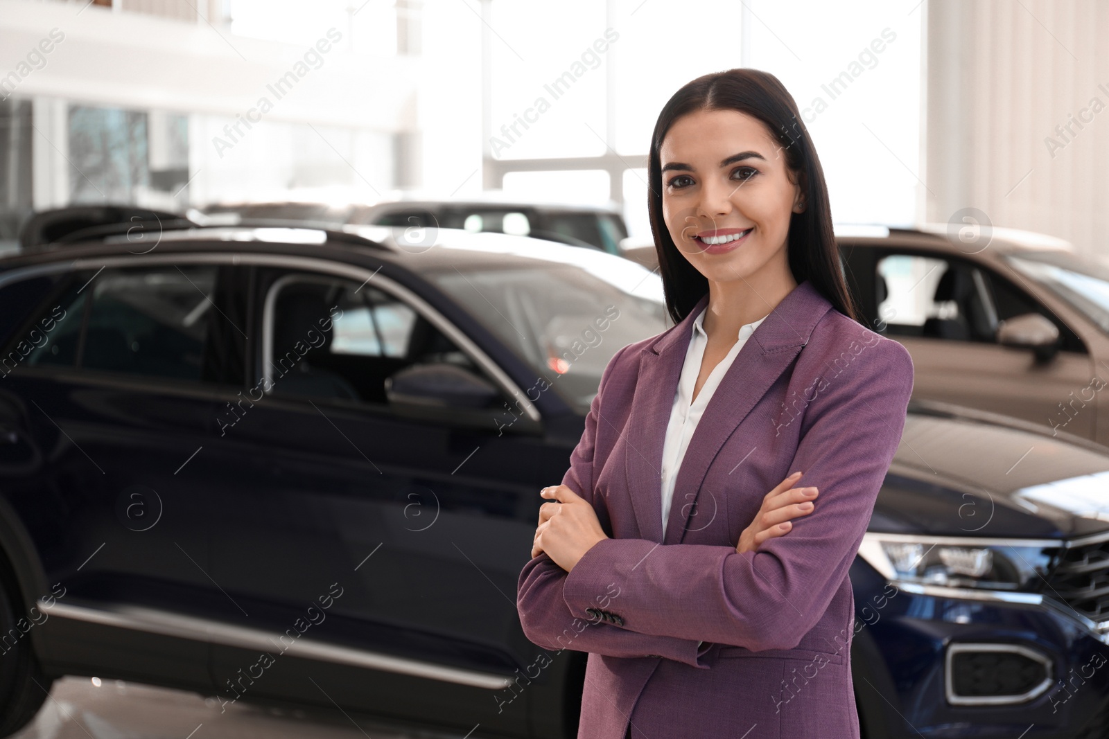 Photo of Happy young saleswoman in modern car salon