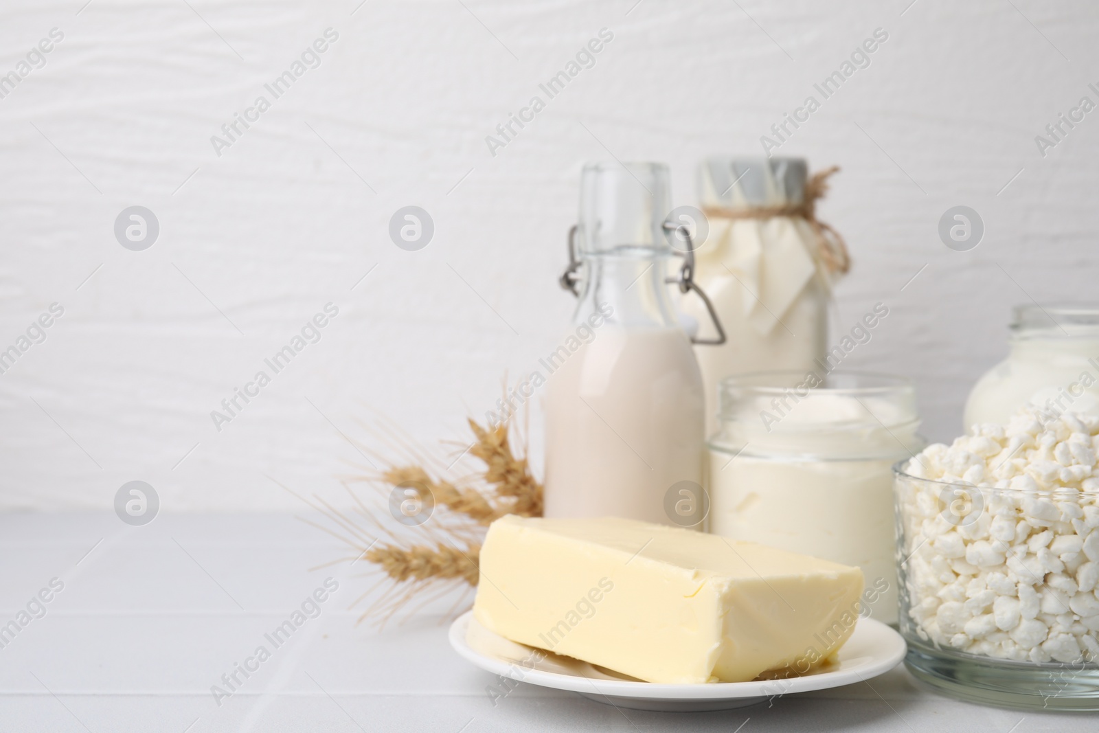 Photo of Different dairy products and spikes on white table, space for text