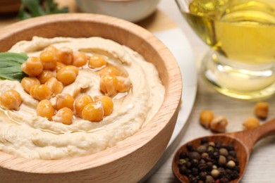 Photo of Bowl with delicious hummus and chickpeas on table, closeup