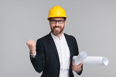 Architect in hard hat with drafts on gray background
