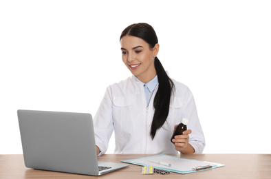 Photo of Professional pharmacist working with laptop at table against white background