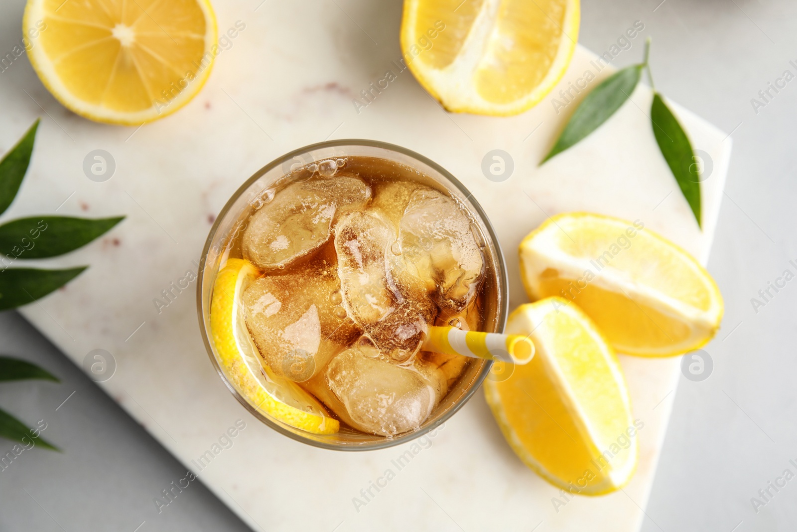 Photo of Glass of lemonade with ice cubes and fruit on table, flat lay