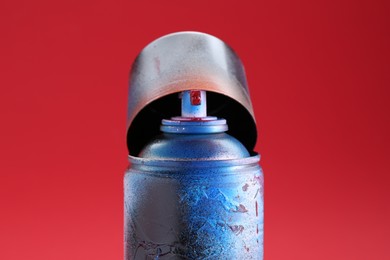 Photo of One can of bright spray paint with cap on red background, closeup
