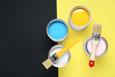 Photo of Cans of different paints and brushes on color background, flat lay. Space for text