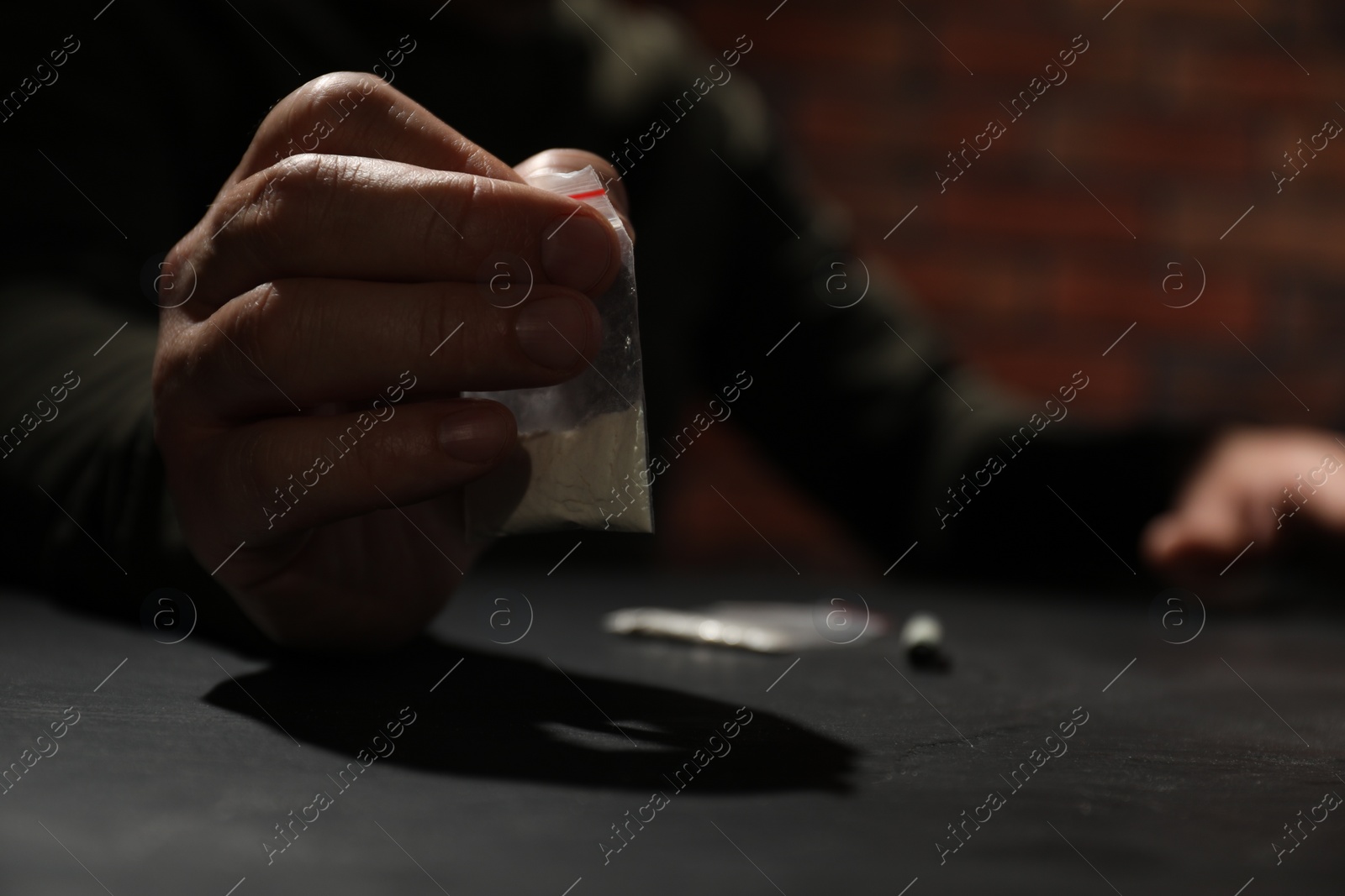 Photo of Drug addiction. Man with plastic bag of cocaine at grey table, selective focus