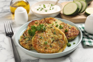 Photo of Delicious zucchini fritters served on white marble table