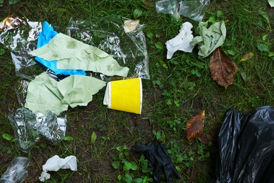 Photo of Garbage scattered on green grass in park, flat lay
