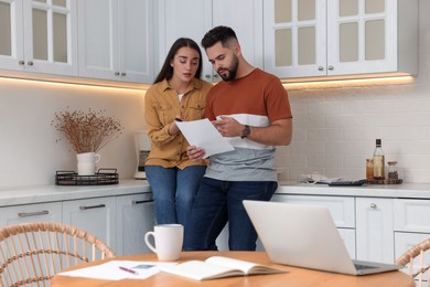 Young couple discussing family budget in kitchen
