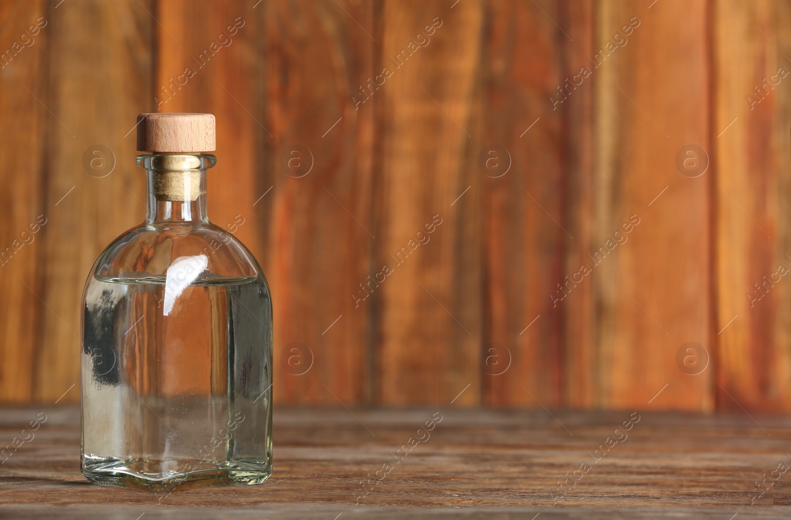 Photo of Glass bottle with vinegar on wooden background. Space for text