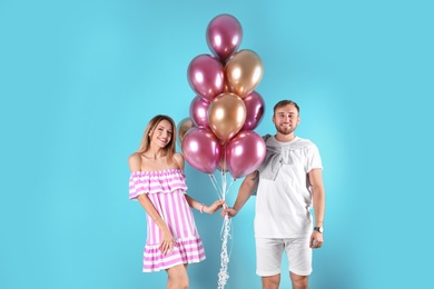 Photo of Young couple with air balloons on color background