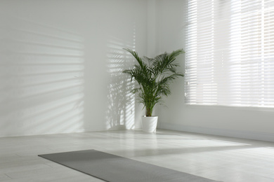 Photo of Unrolled grey yoga mat on floor in room. Space for text