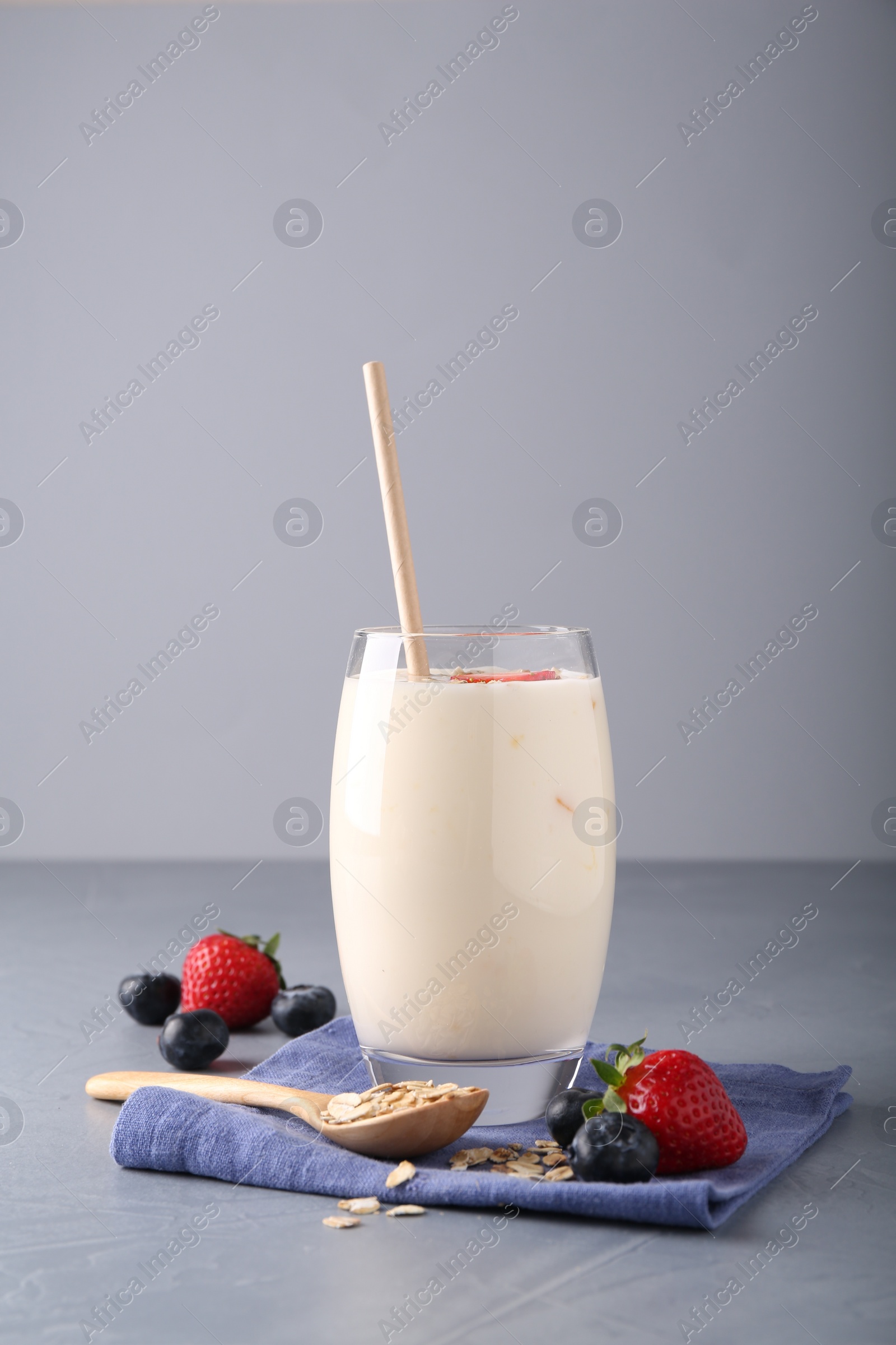 Photo of Tasty yogurt in glass, oats and berries on grey table