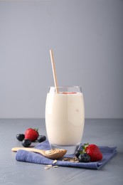 Photo of Tasty yogurt in glass, oats and berries on grey table