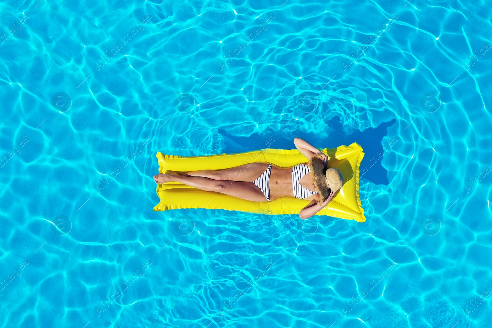 Image of Young woman with inflatable mattress in swimming pool, top view