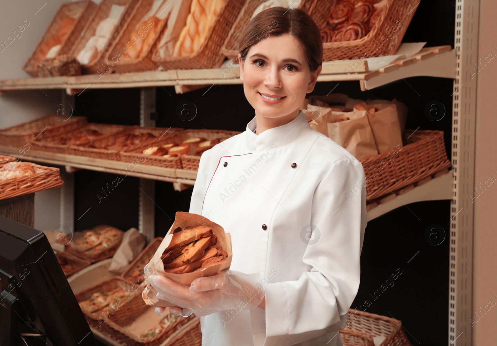 Photo of Professional baker holding paper bag with pastry in store