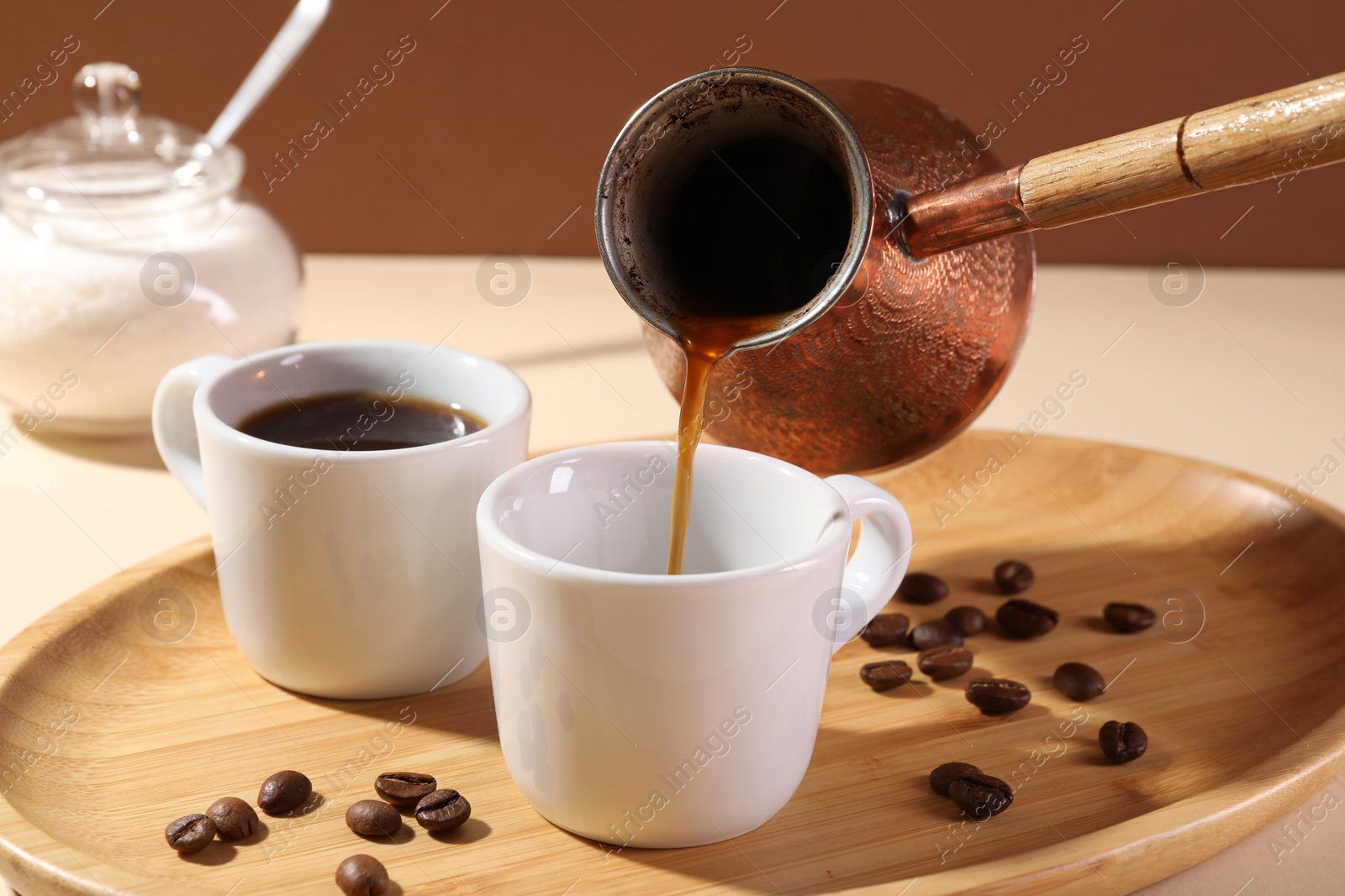 Photo of Pouring aromatic coffee from cezve into cup at table, closeup