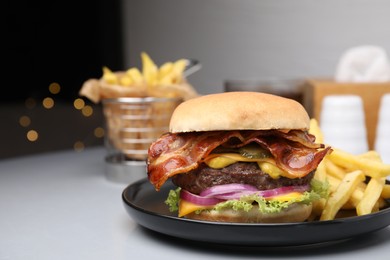 Photo of Tasty burger with bacon, vegetables and patty served with french fries on light grey table, closeup. Space for text