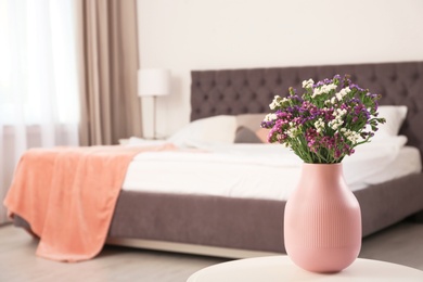 Photo of Beautiful flowers in vase and space for text on blurred background. Element of interior design