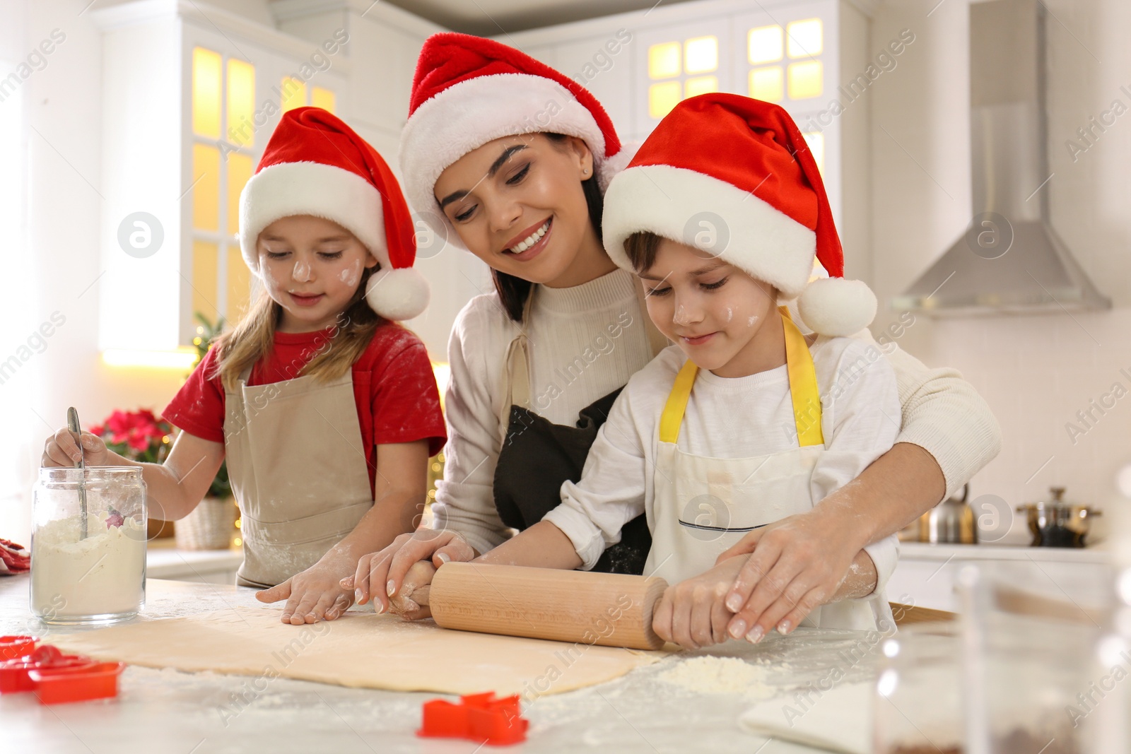 Photo of Mother and her cute little children making Christmas cookies in kitchen