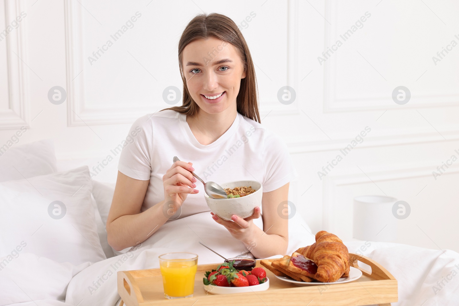 Photo of Smiling woman having tasty breakfast in bed at home