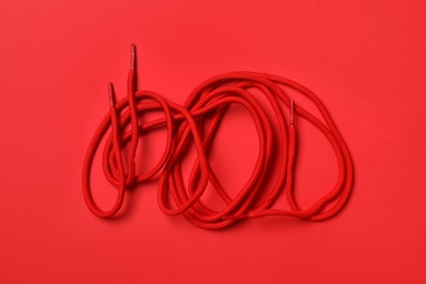 Photo of Shoelaces on red background, flat lay. Stylish accessory