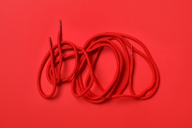 Shoelaces on red background, flat lay. Stylish accessory