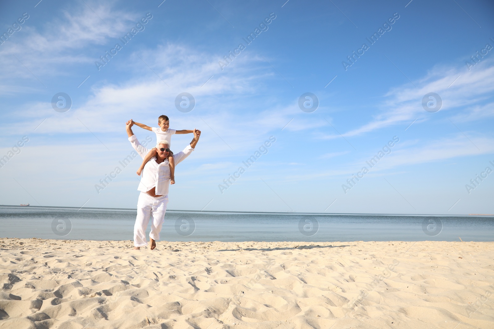 Photo of Cute little boy with grandfather spending time together on sea beach