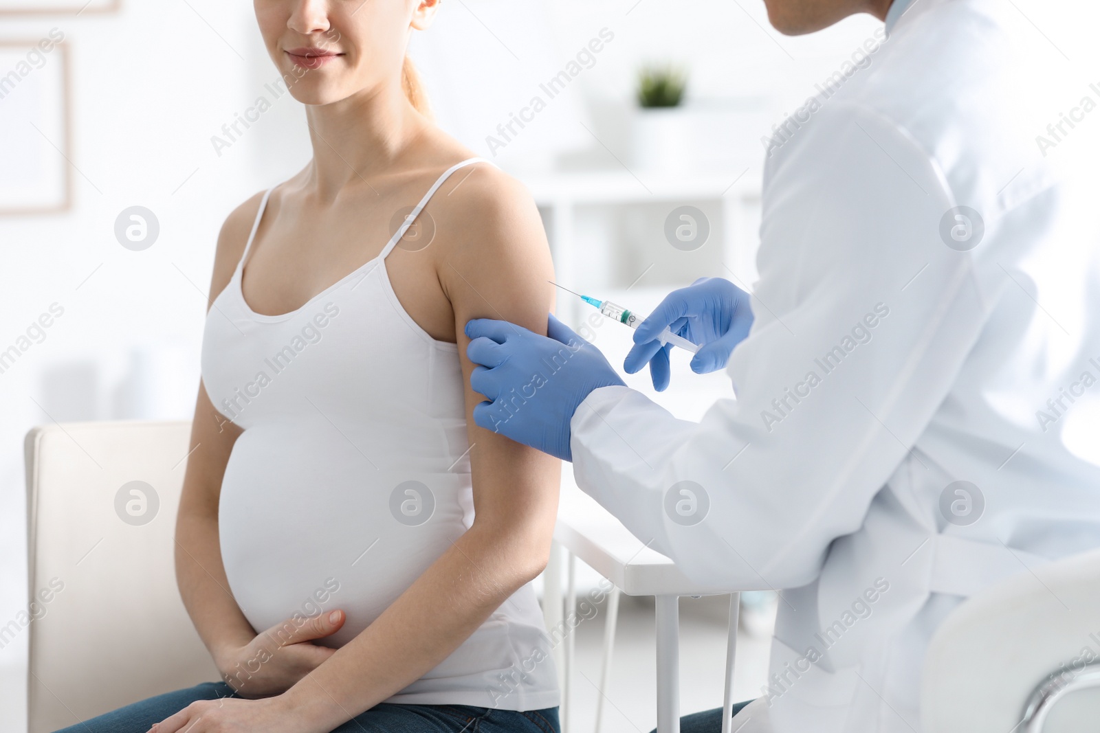 Photo of Doctor giving injection to pregnant woman in hospital, closeup. Vaccination concept