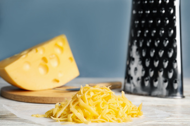 Tasty grated cheese on white wooden table